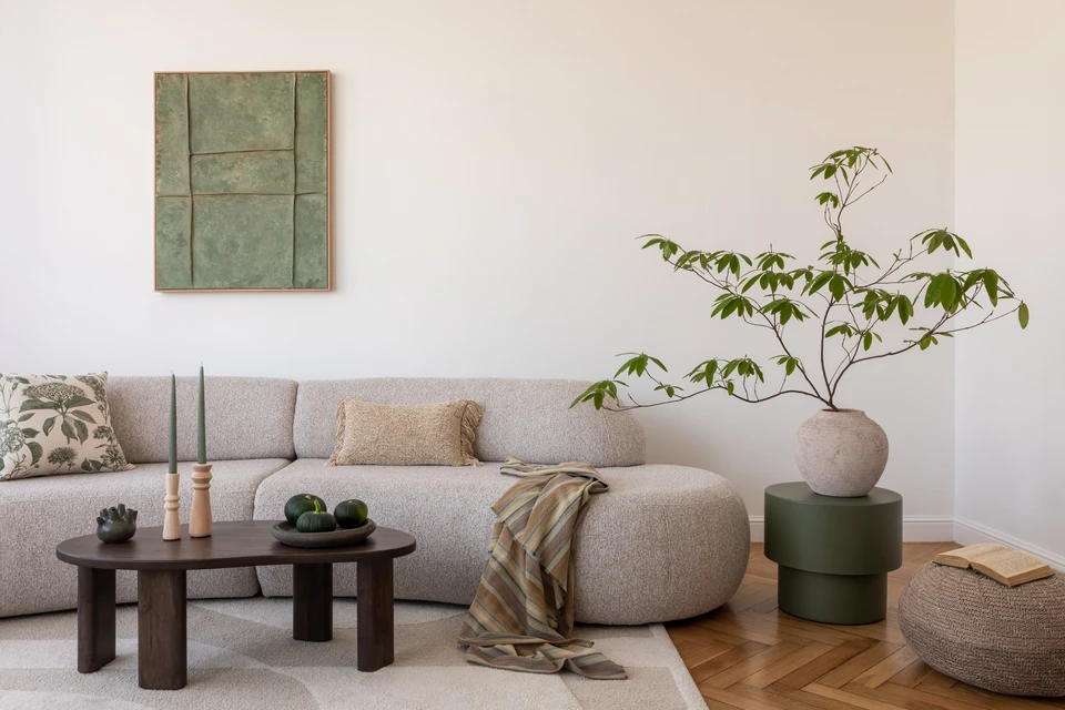 Salon confortable avec une section douce, table basse rustique, et des plantes luxuriantes, parfait pour se détendre dans le style