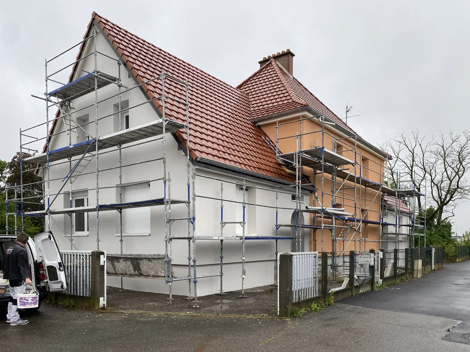 Chantier de construction intérieure avec ouvrier en gilet haute visibilité travaillant dans un espace en cours d'aménagement