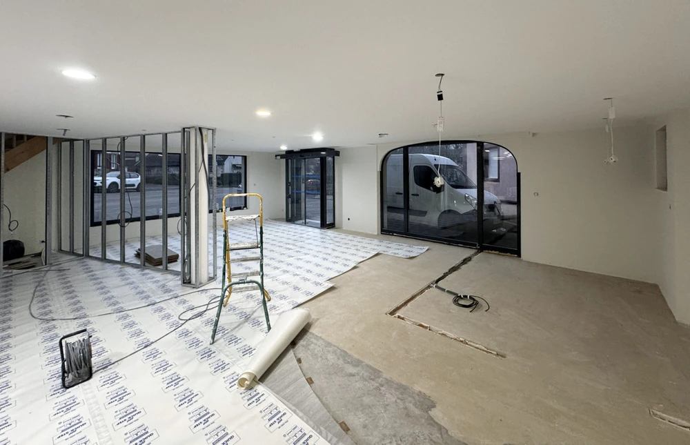 Chantier de rénovation intérieure en cours avec ouvriers en équipements de sécurité travaillant dans un espace commercial ou résidentiel