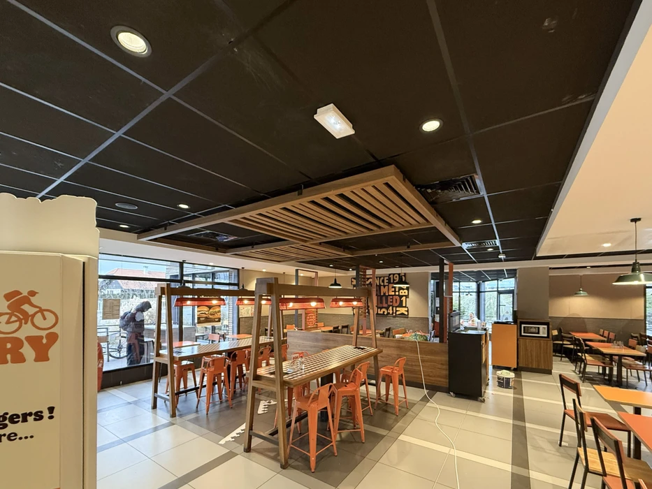 Espace de présentation commercial moderne avec cuisine ouverte équipée d'îlot central, tabourets hauts et grande table de réunion ovale