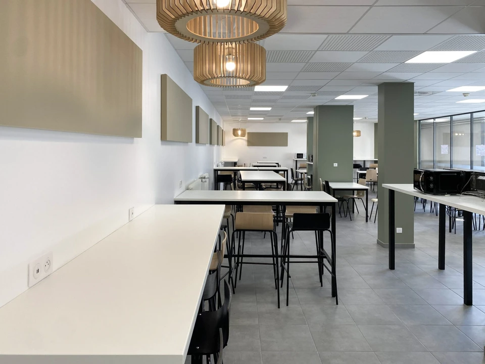 Équipe professionnelle diverse posant dans bureau moderne avec murs en briques apparentes et grandes fenêtres cintrées