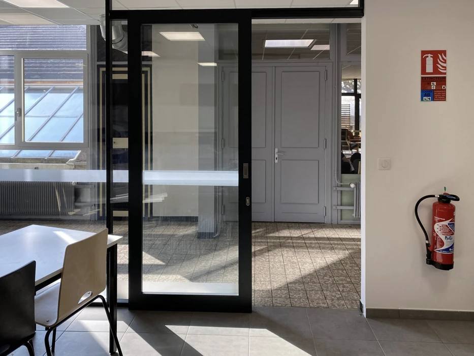 Espace de restauration d'entreprise moderne avec tables hautes et chaises, cuisine ouverte intégrée