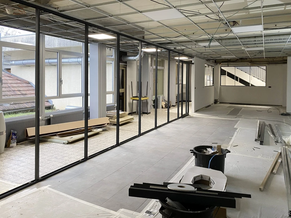 Espace de restauration d'entreprise moderne avec tables hautes et chaises, cuisine ouverte intégrée