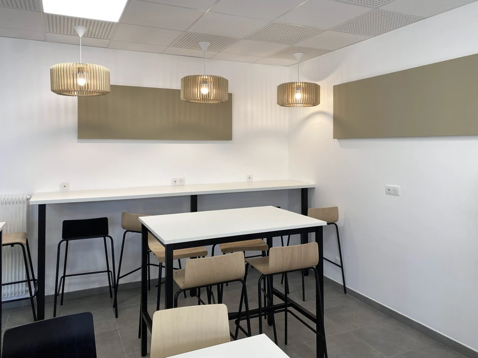 Espace de restauration d'entreprise moderne avec tables hautes et chaises, cuisine ouverte intégrée