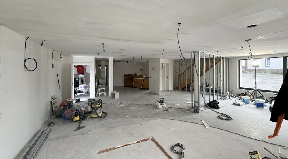 Espace de restauration d'entreprise moderne avec tables hautes et chaises, cuisine ouverte intégrée