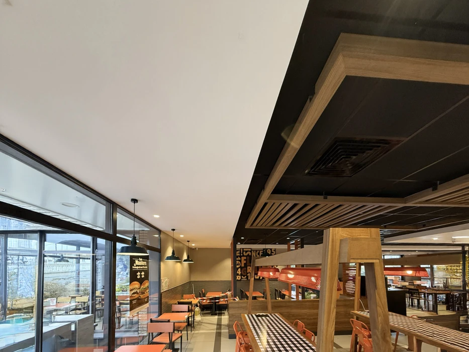 Espace de restauration d'entreprise moderne avec tables hautes et chaises, cuisine ouverte intégrée