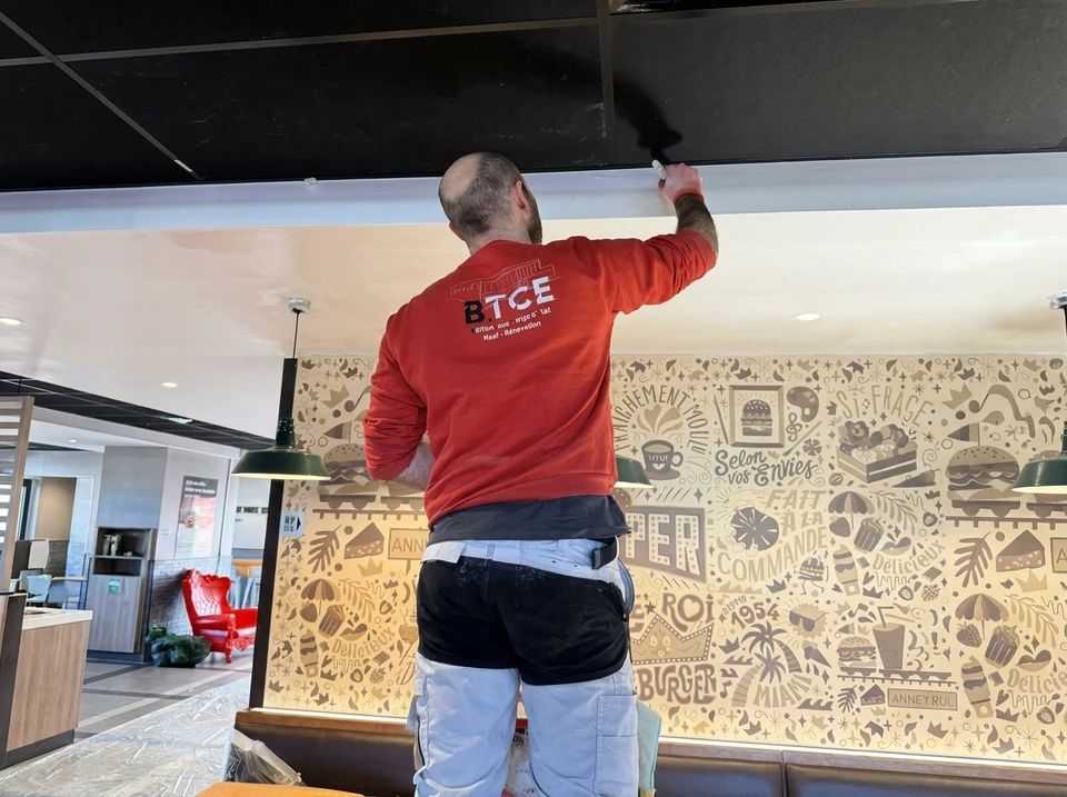 Vue arrière de deux peintres masculins planifiant la rénovation de l'appartement, tenant un rouleau à peinture, travaillant sur l'amélioration de la maison ou la rénovation