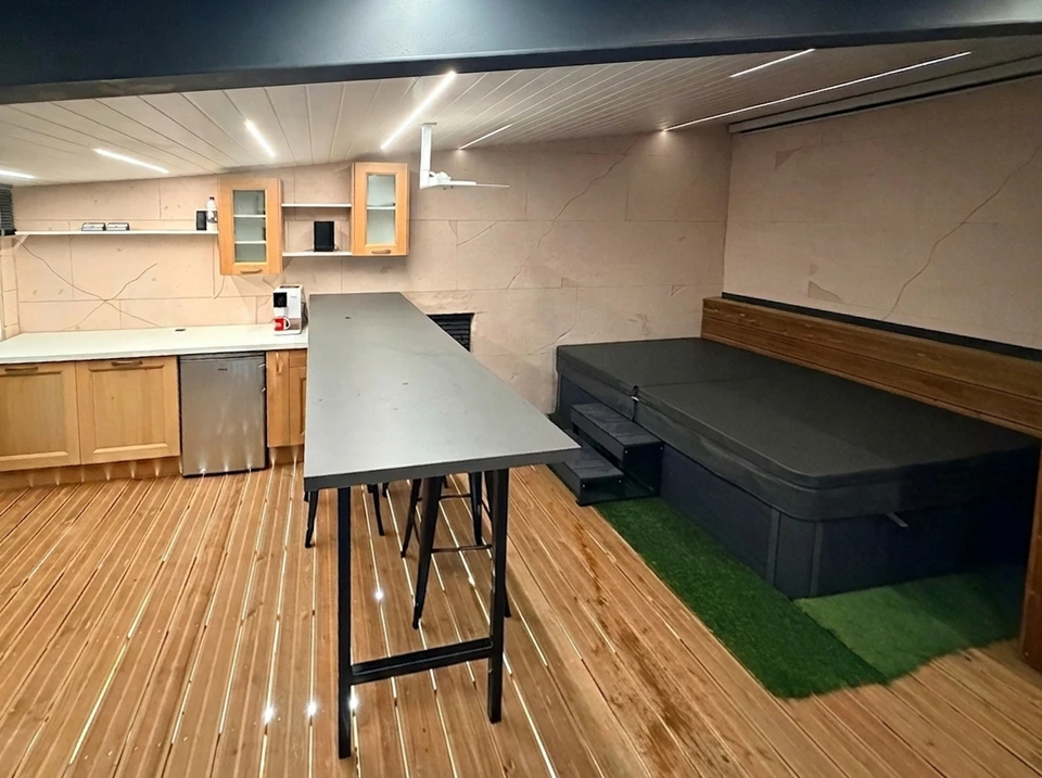 Salon moderne minimaliste avec canapé blanc, table basse en bois clair, étagère organisée avec paniers de rangement, chaise tressée et plante verte près d'une grande fenêtre à carreaux