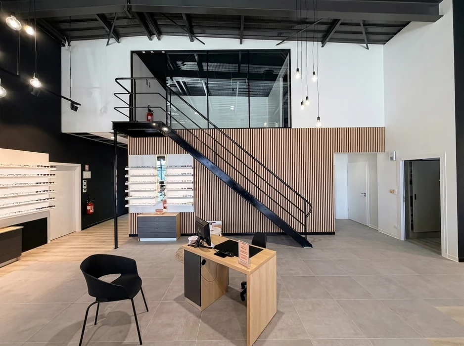 Espace de présentation commercial moderne avec cuisine ouverte équipée d'îlot central, tabourets hauts et grande table de réunion ovale